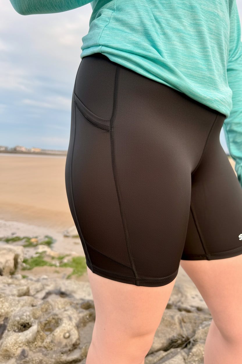 Person wearing brown shorts with a blurred beach background