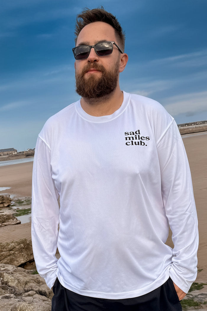 Man wearing a white long-sleeve shirt with text on a beach