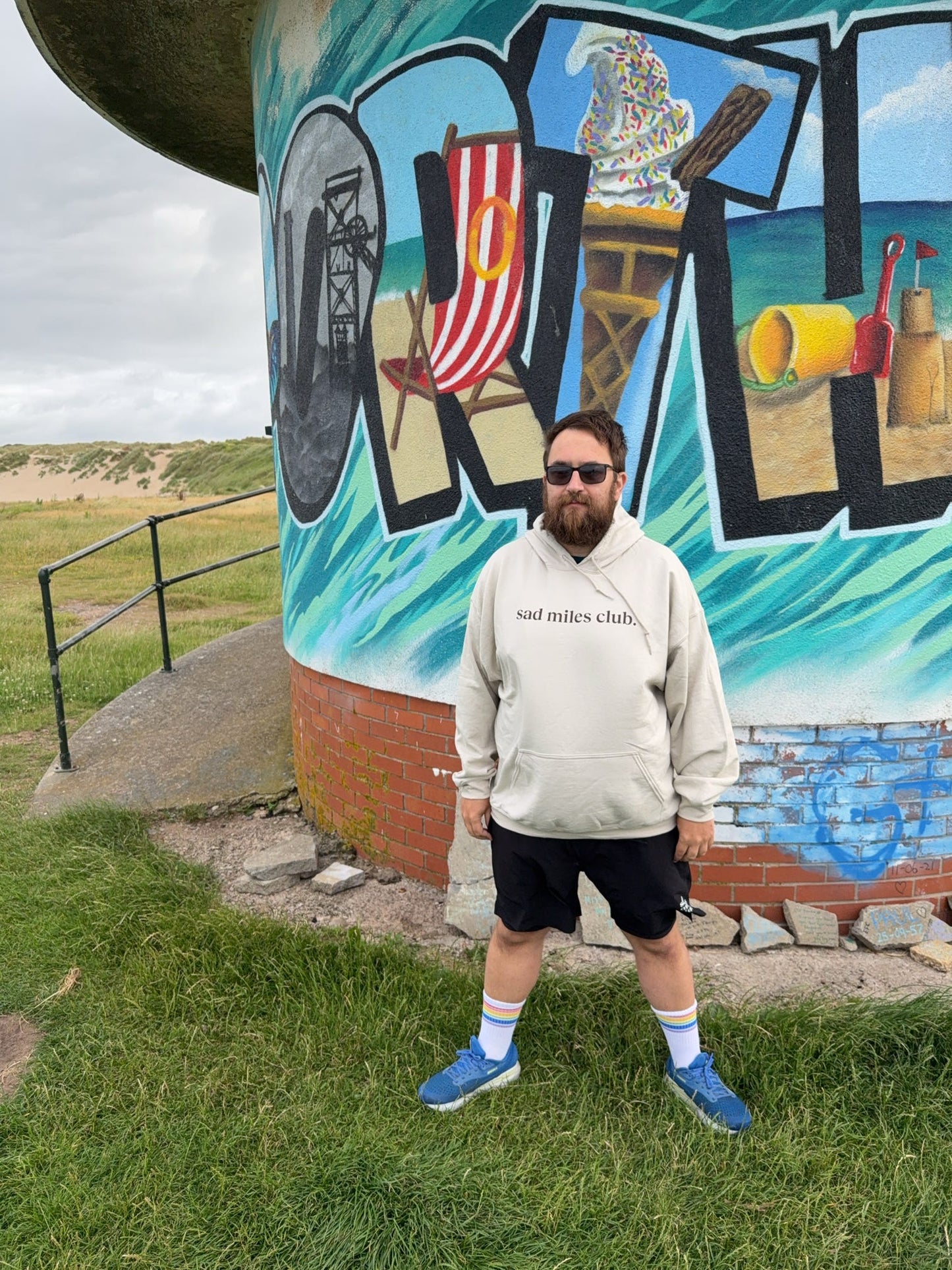 Person standing in front of a colorful mural with text and graphics.
